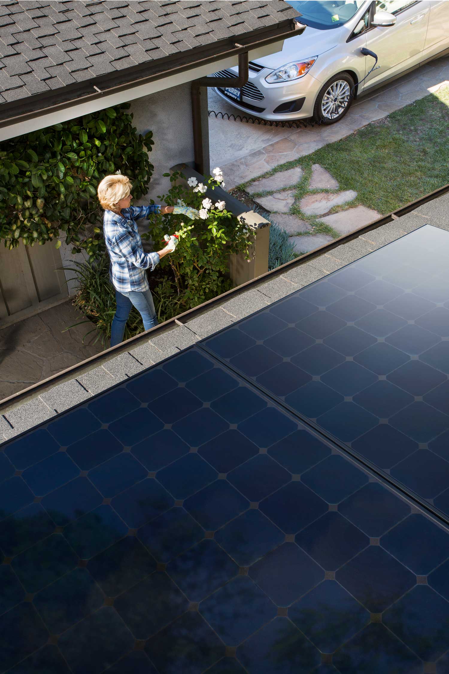 Image of a woman below her solar panels - learn why cleaning your solar panels is important with experts at Custom Energy.